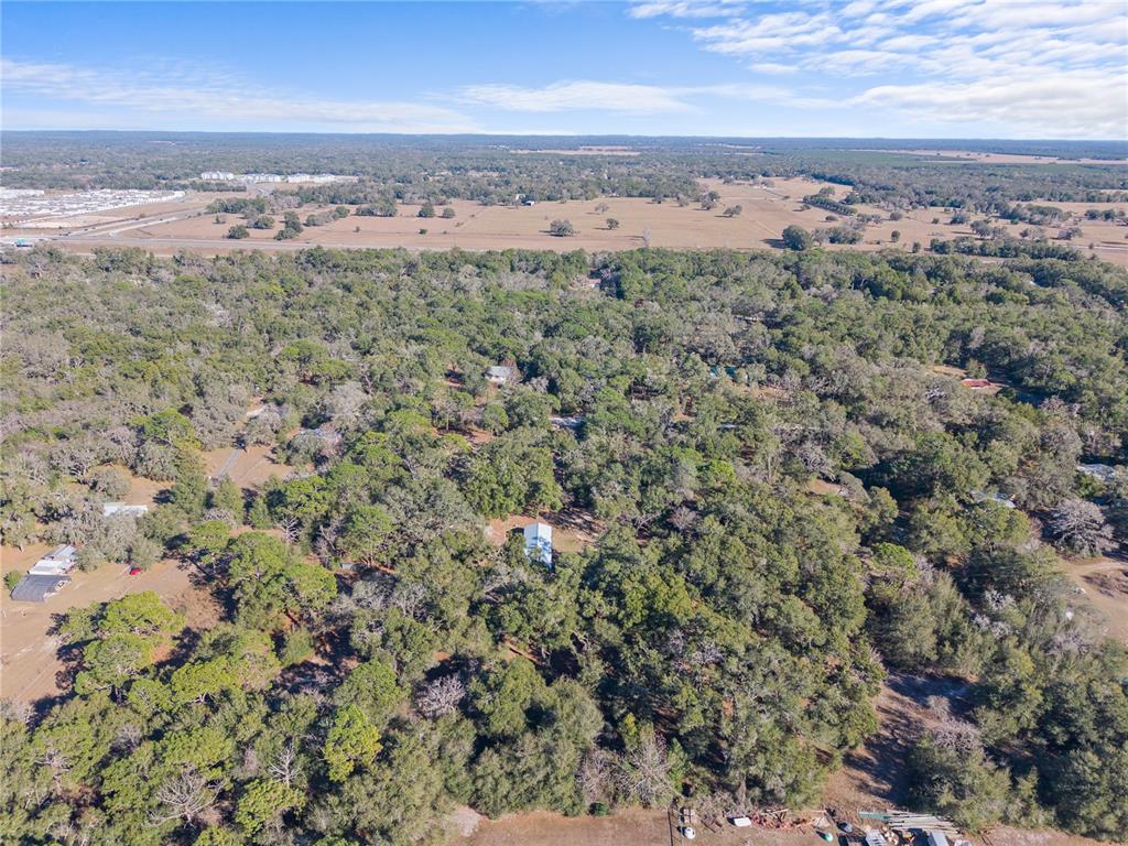 An aerial view shows a house nestled within a dense forest near open fields — 0 DEASON DRIVE, SPRING HILL, FL