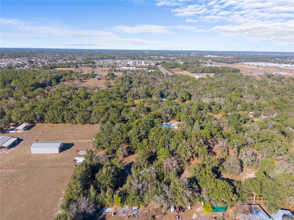 An aerial view shows a large, wooded lot with several outbuildings and a residential house — 0 DEASON DRIVE, SPRING HILL, FL