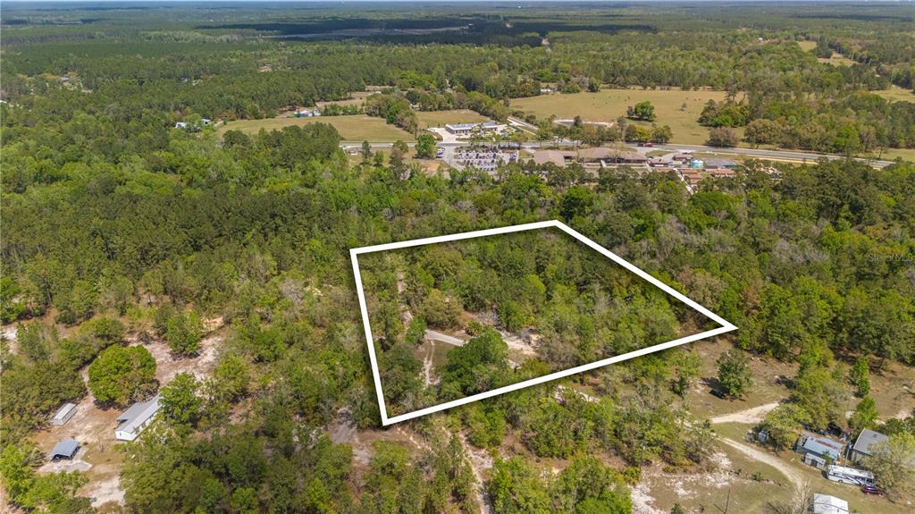 An aerial view shows a rectangular plot of land outlined in white amidst wooded terrain — COUNTY ROAD 218, JACKSONVILLE, FL