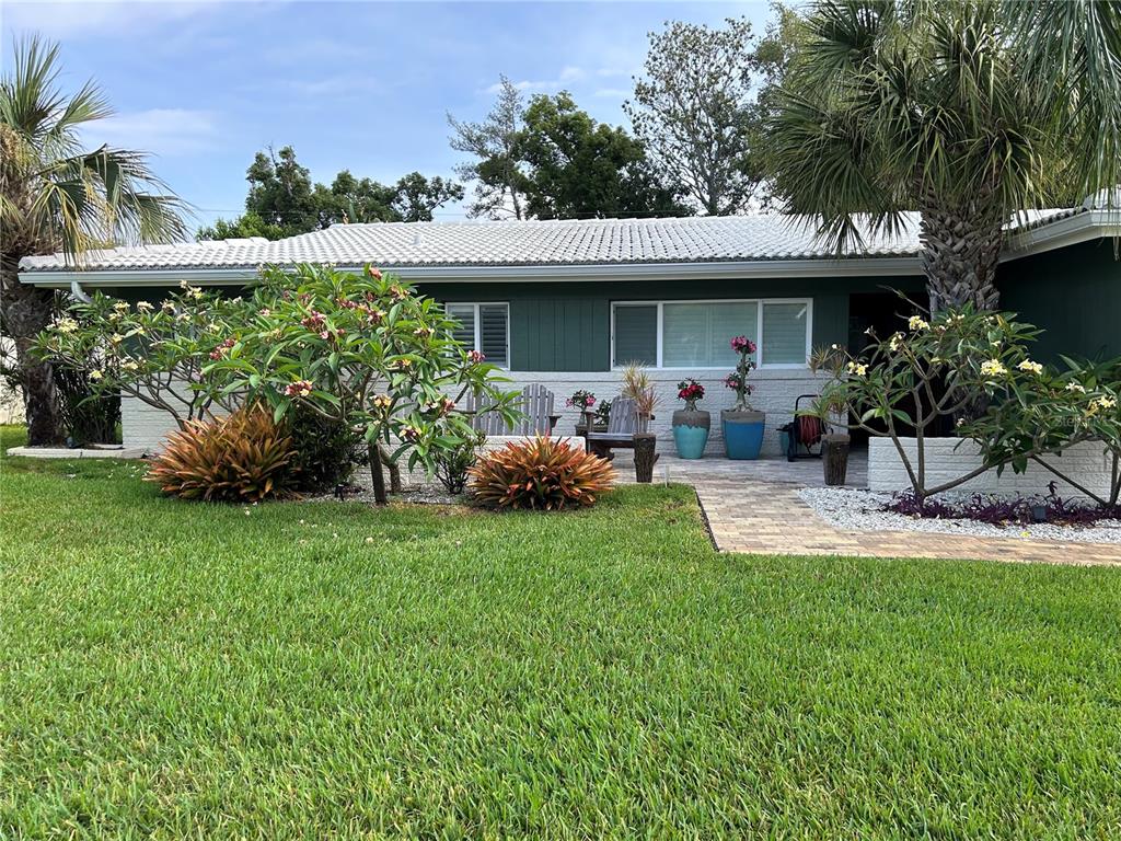 A single-story house with a green exterior, white roof, and a landscaped front patio area — 2058 NURSERY ROAD, CLEARWATER, FL