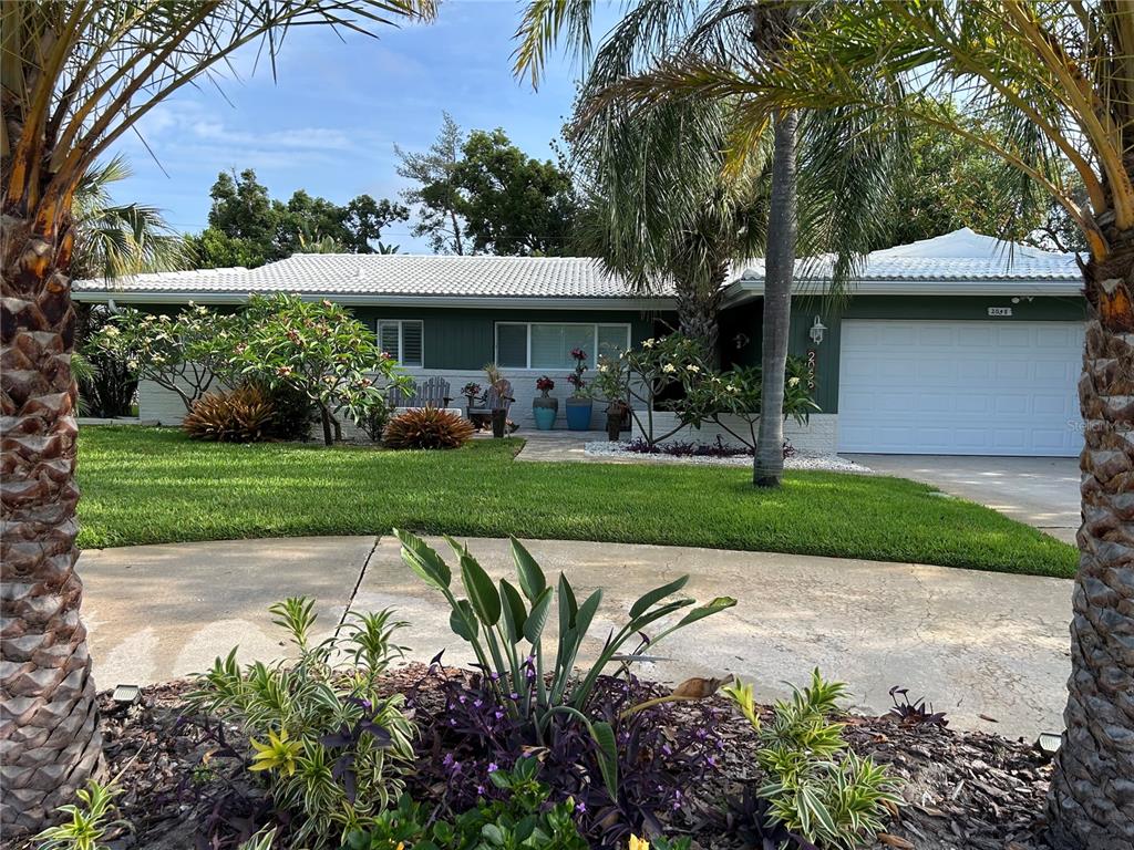 A single-story house with a white tile roof, green siding, and a two-car garage — 2058 NURSERY ROAD, CLEARWATER, FL