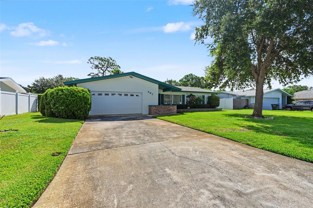 A single-story house with a concrete driveway, a two-car garage, and a large front lawn — 981 STEPHEN FOSTER DRIVE, LARGO, FL