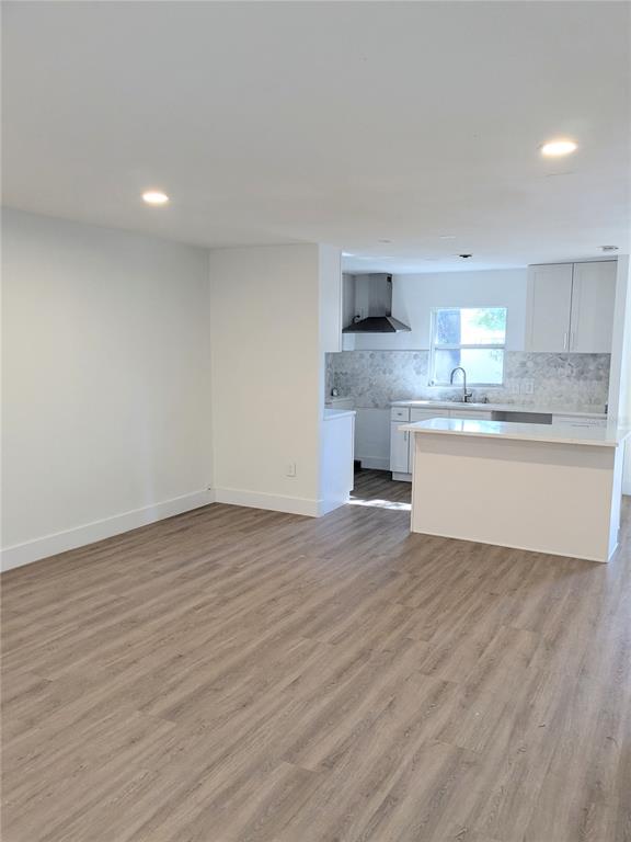 An open-concept room features light wood-look flooring, white walls, and a modern kitchen with white cabinets — 3006 E ANDERSON STREET, ORLANDO, FL
