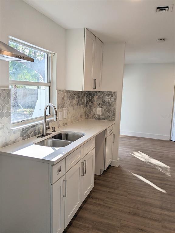 A kitchen features white cabinets, a stainless steel sink, and a gray hexagonal tile backsplash — 3006 E ANDERSON STREET, ORLANDO, FL