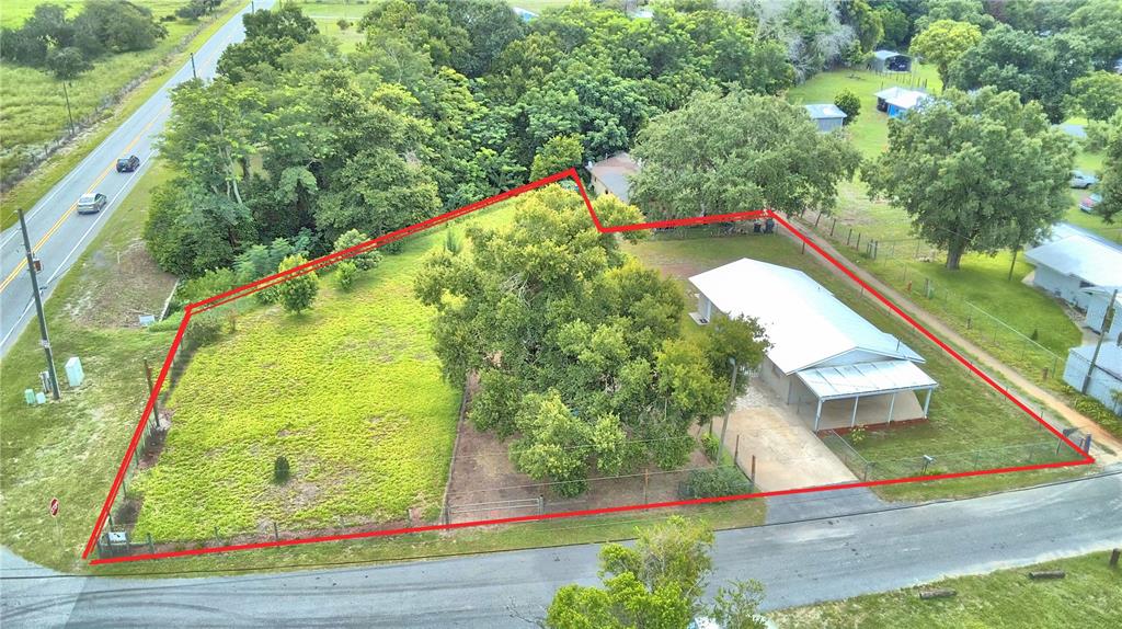 An aerial view shows a fenced residential lot with a house, large trees, and grass — 30 MONK ROAD, FROSTPROOF, FL