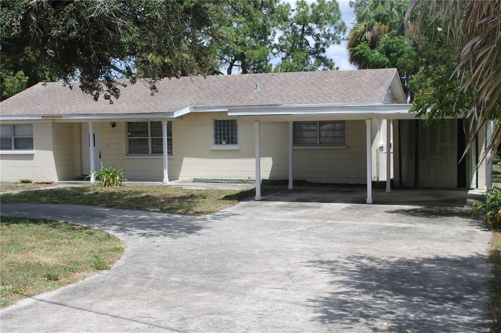 A single-story house with a light-colored exterior, a concrete driveway, and an attached carport — 2337 N CRYSTAL LAKE DRIVE, LAKELAND, FL