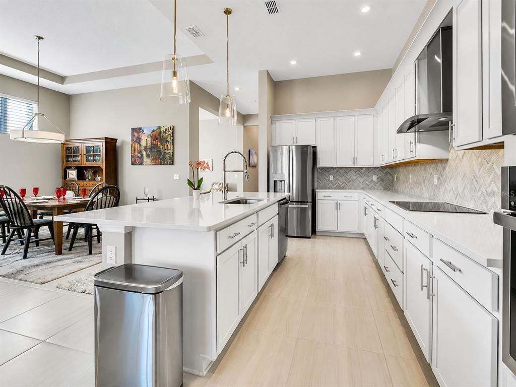 A modern kitchen features white cabinetry, a large quartz island, and stainless steel appliances — 891 MEGANO BOULEVARD, DELAND, FL