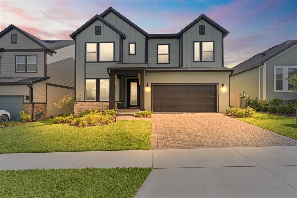 A two-story house with sage green siding, a dark garage, and a paved driveway — 16983 CEDAR VALLEY CIRCLE, CLERMONT, FL