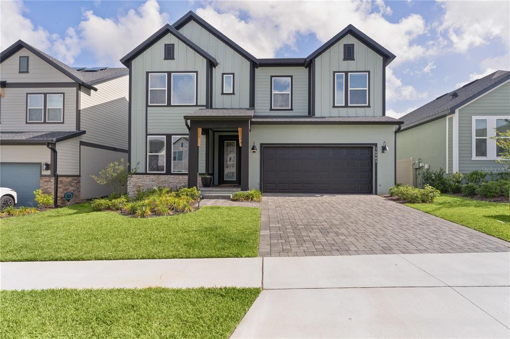 A two-story house with light green vertical siding, a dark garage, and a paved driveway — 16983 CEDAR VALLEY CIRCLE, CLERMONT, FL