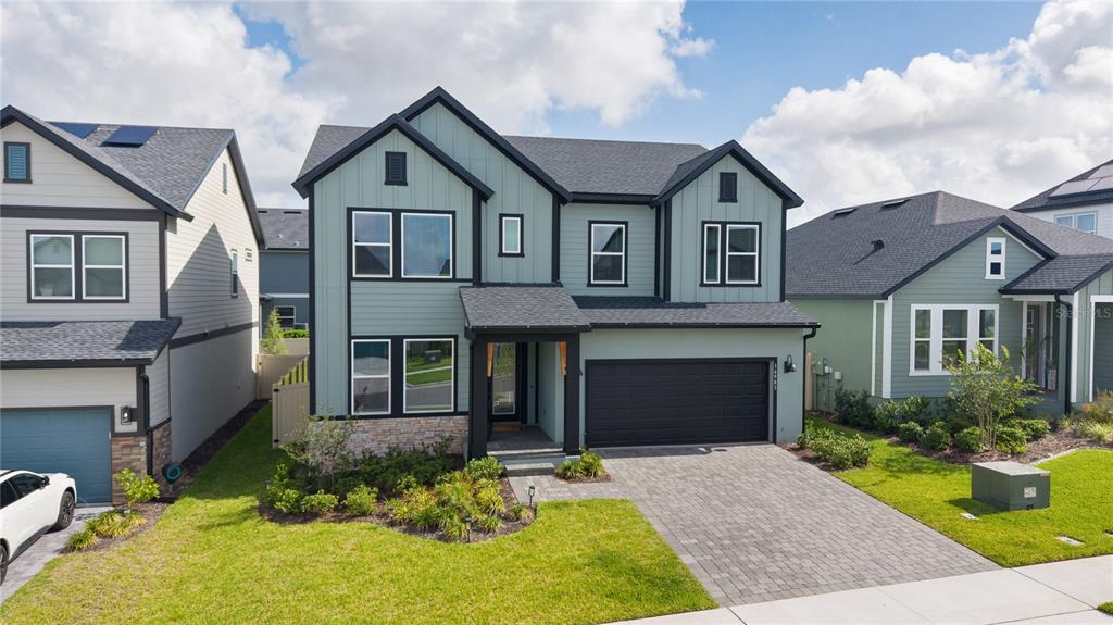 A two-story house with sage green vertical siding, a black garage door, and stone accents — 16983 CEDAR VALLEY CIRCLE, CLERMONT, FL