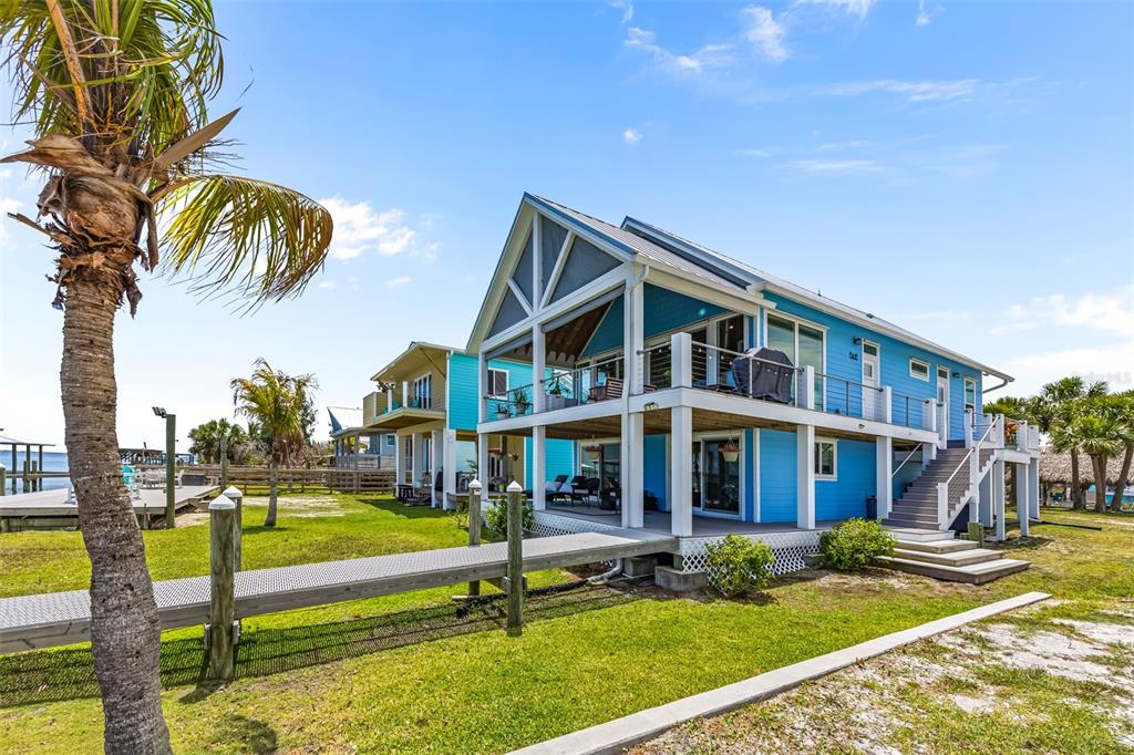 A bright blue two-story house with a wooden walkway and a palm tree outside — 18 VIP ISLAND B, GRANT, FL