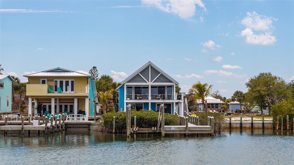 Two colorful waterfront houses stand behind wooden docks on a sunny day — 18 VIP ISLAND B, GRANT, FL