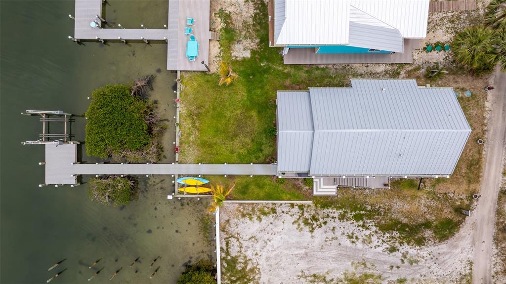 An aerial view shows a waterfront house with a metal roof, a dock, and kayaks — 18 VIP ISLAND B, GRANT, FL