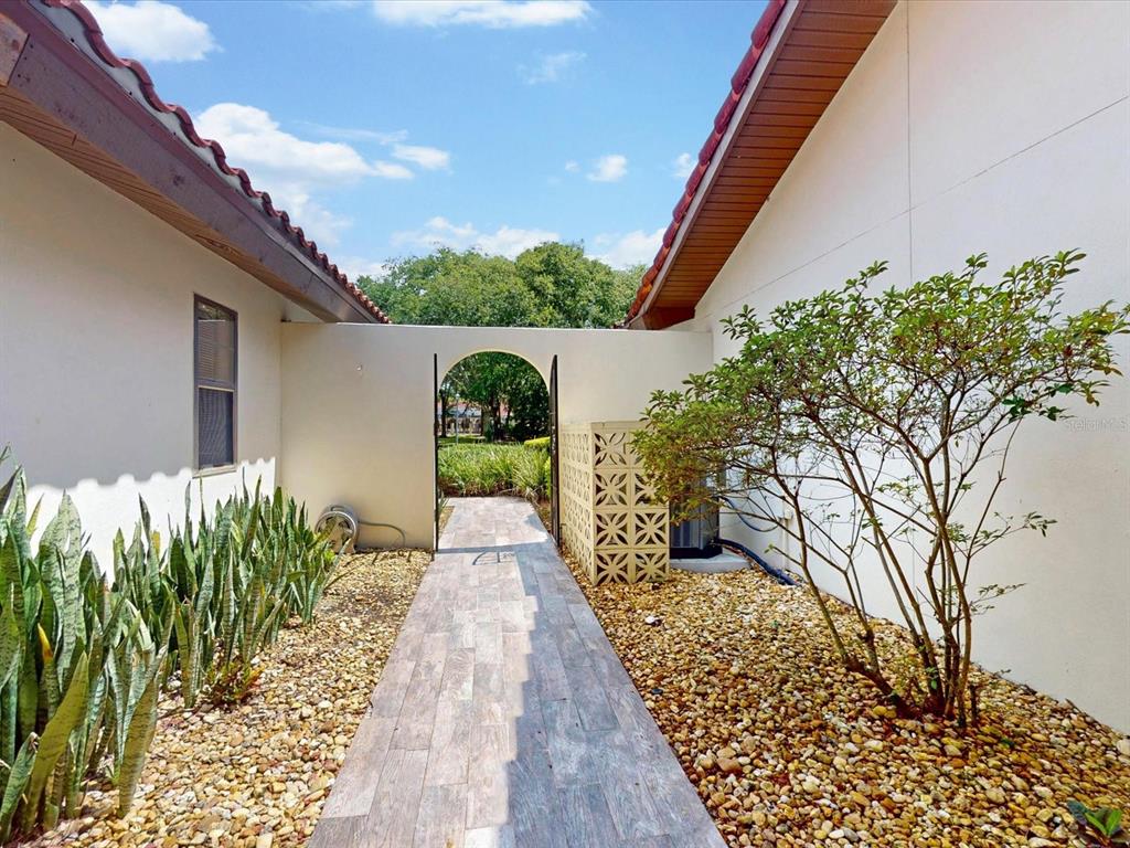 A paved walkway leads through an arched gate between two sections of a stucco house — 105 COVENTRY LANE, HAINES CITY, FL