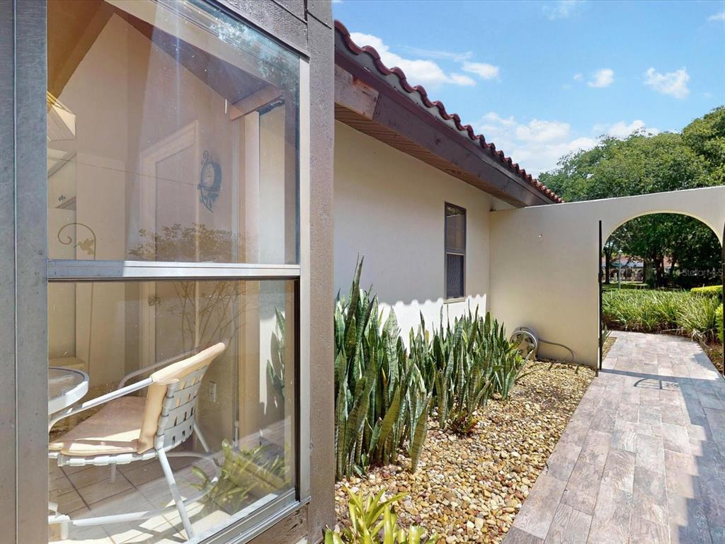 A view through a window shows a patio with a chair next to a walkway — 105 COVENTRY LANE, HAINES CITY, FL