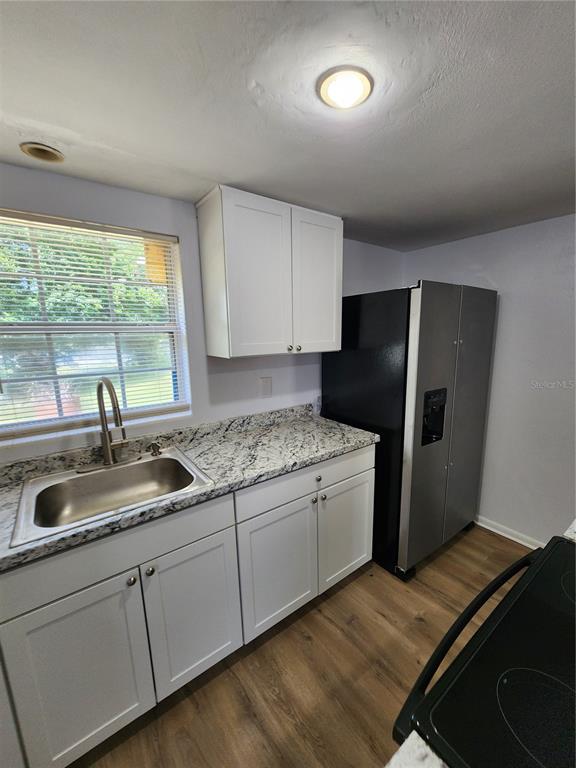 A kitchen features white cabinets, granite countertops, a stainless steel sink, and a refrigerator — 3 E LEMON STREET, BEVERLY HILLS, FL