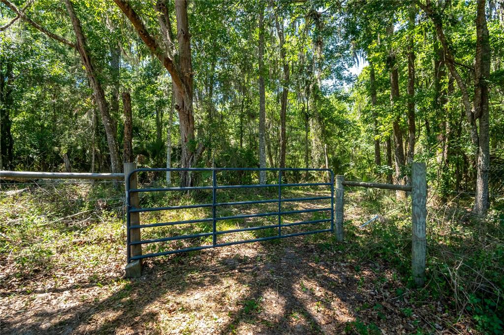 A metal gate stands between two wooden posts at the entrance to a wooded area — 00 NW HWY 225, REDDICK, FL