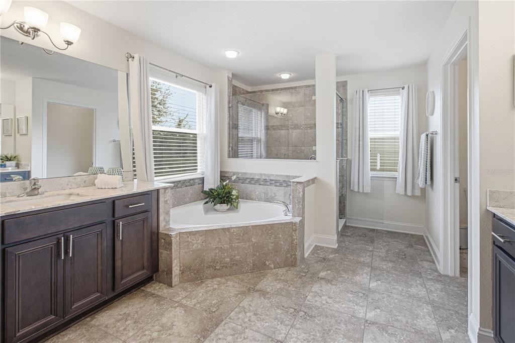 A bathroom featuring a corner soaking tub, a glass-enclosed shower, and dark wood vanity cabinets — 52 CROSSWOOD COURT, ST AUGUSTINE, FL