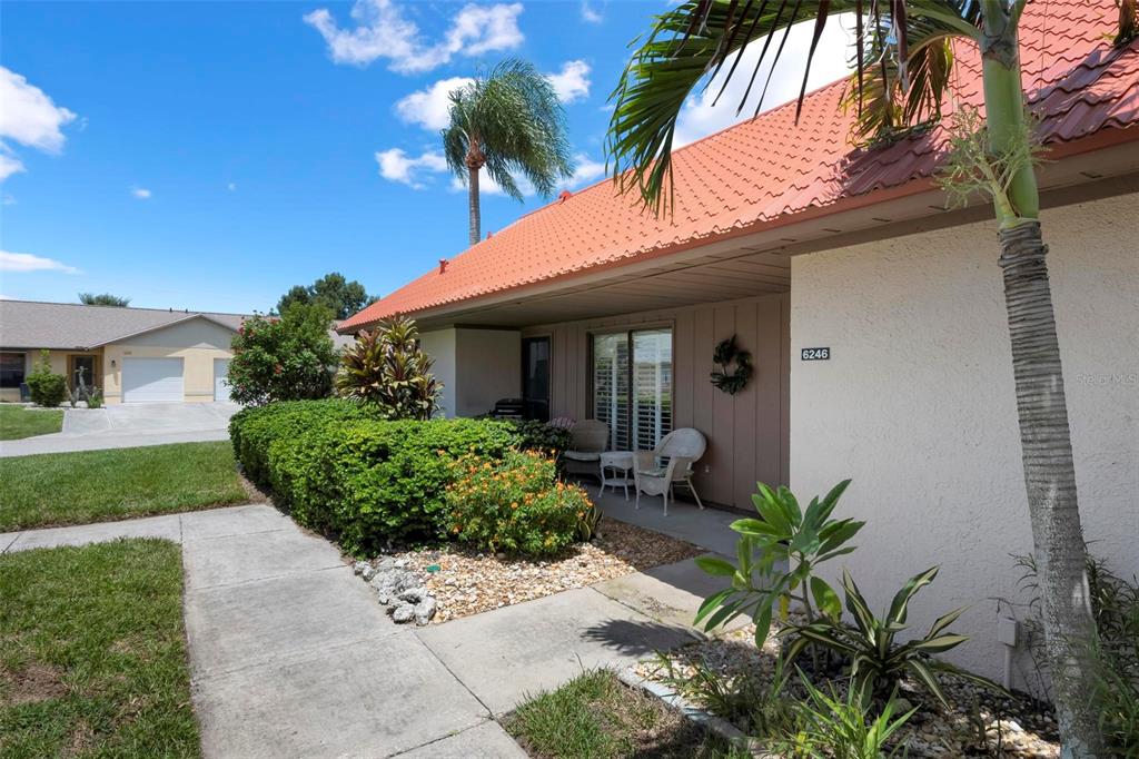 A living room features a vaulted ceiling, a patterned rug, and sliding glass doors — 6246 DRAW LANE UNIT 12, SARASOTA, FL
