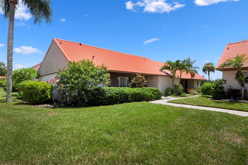 A living room with a vaulted ceiling, a gray sofa, two armchairs, and a dining area — 6246 DRAW LANE UNIT 12, SARASOTA, FL