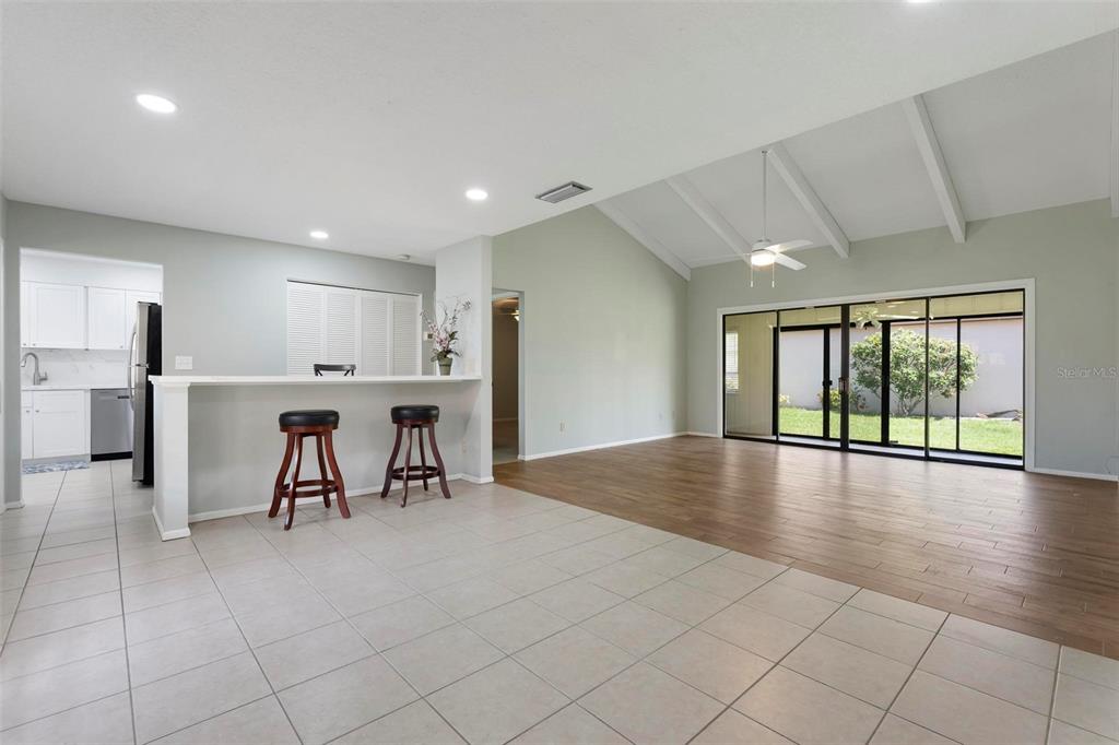 A living room with vaulted ceilings, wood-look flooring, and a breakfast bar overlooking the kitchen — 6246 DRAW LANE UNIT 12, SARASOTA, FL