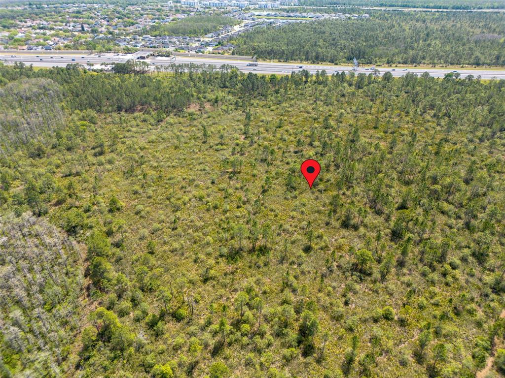 An aerial view shows a wooded lot with a red location pin and a highway nearby — INTERNATIONAL DRIVE, ORLANDO, FL
