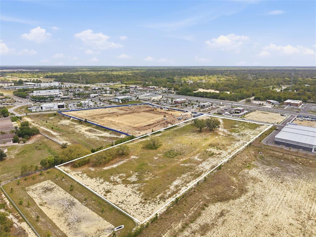 An aerial view shows a large, cleared rectangular plot of land bordered by white fencing — QUALITY DRIVE, SPRING HILL, FL