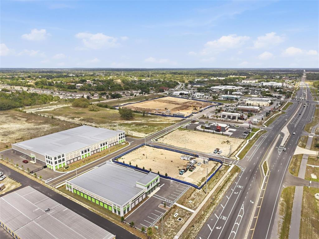 An aerial view shows commercial buildings and undeveloped lots adjacent to a multi-lane road — QUALITY DRIVE, SPRING HILL, FL