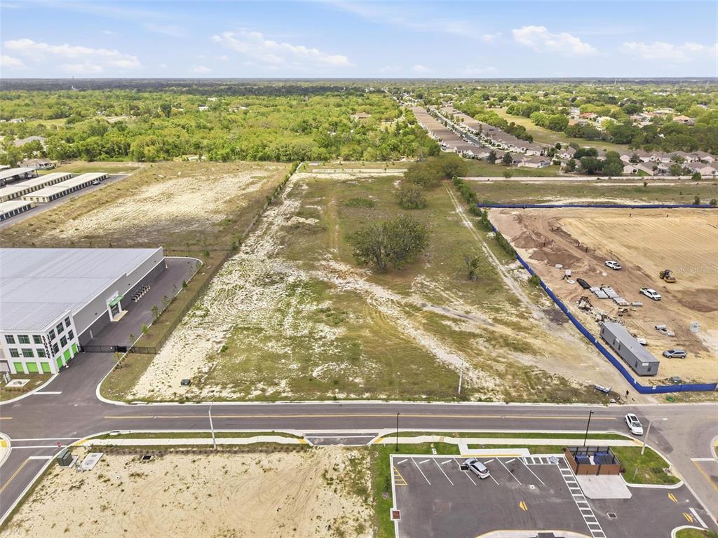 An aerial view shows a vacant rectangular lot bordered by a road, buildings, and construction — QUALITY DRIVE, SPRING HILL, FL