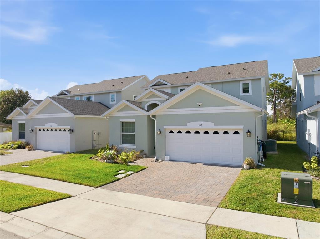 A two-story townhouse with light green siding, a two-car garage, and a paved driveway — 712 REFLECTION LAKE DRIVE, ORLANDO, FL
