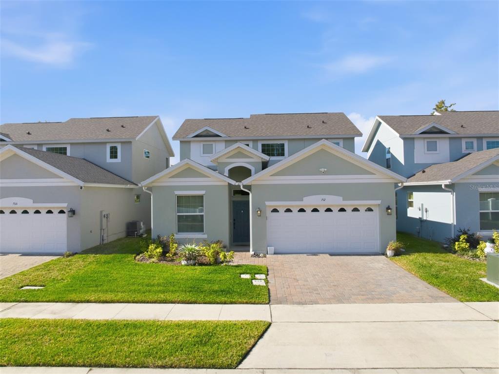 A two-story suburban house with a light green exterior and a two-car garage — 712 REFLECTION LAKE DRIVE, ORLANDO, FL