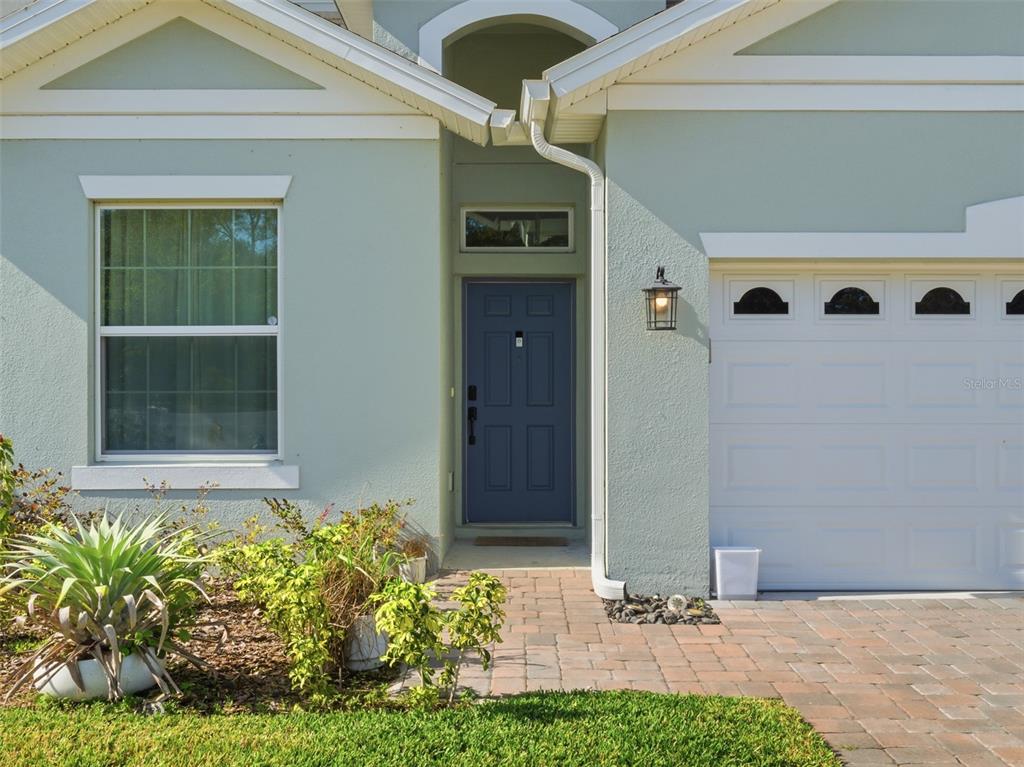 The exterior of a house features a blue front door, a garage, and landscaping — 712 REFLECTION LAKE DRIVE, ORLANDO, FL