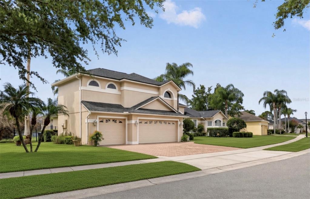 A two-story house exterior at night with a manicured lawn, palm trees, and landscaping — 4552 LAKE CALABAY DRIVE, ORLANDO, FL