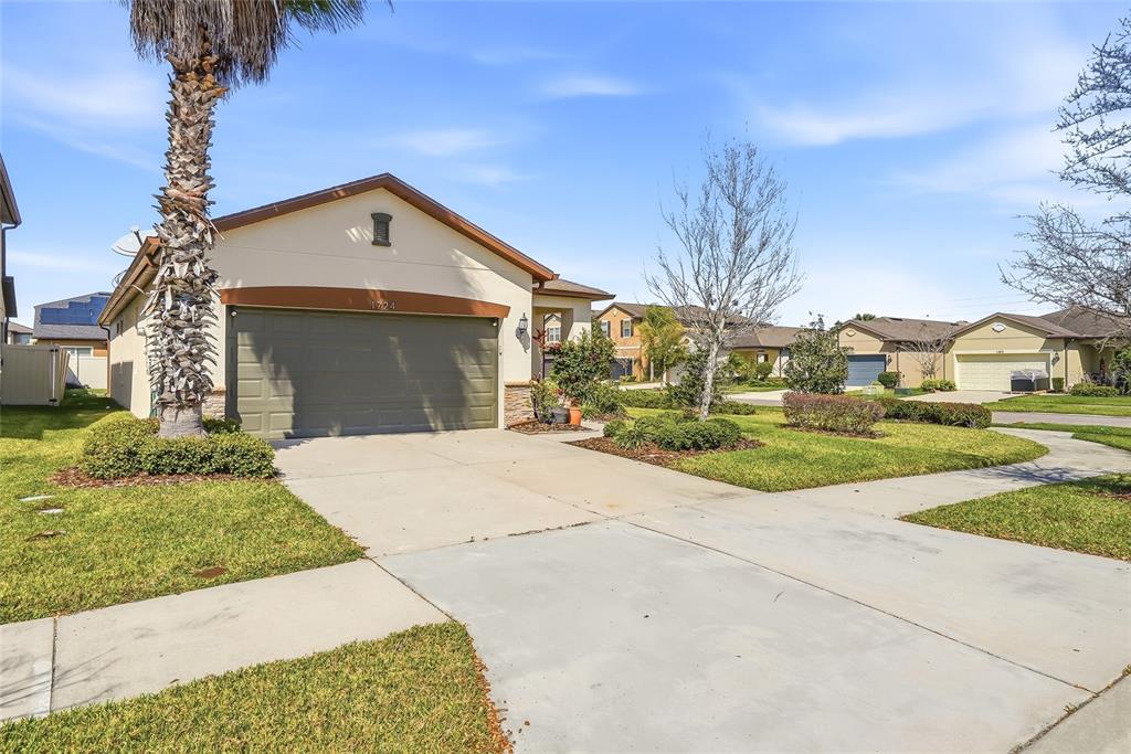 A single-story suburban house with a two-car garage, palm tree, and concrete driveway — 1724 PASSAGE KEY LANE, RUSKIN, FL