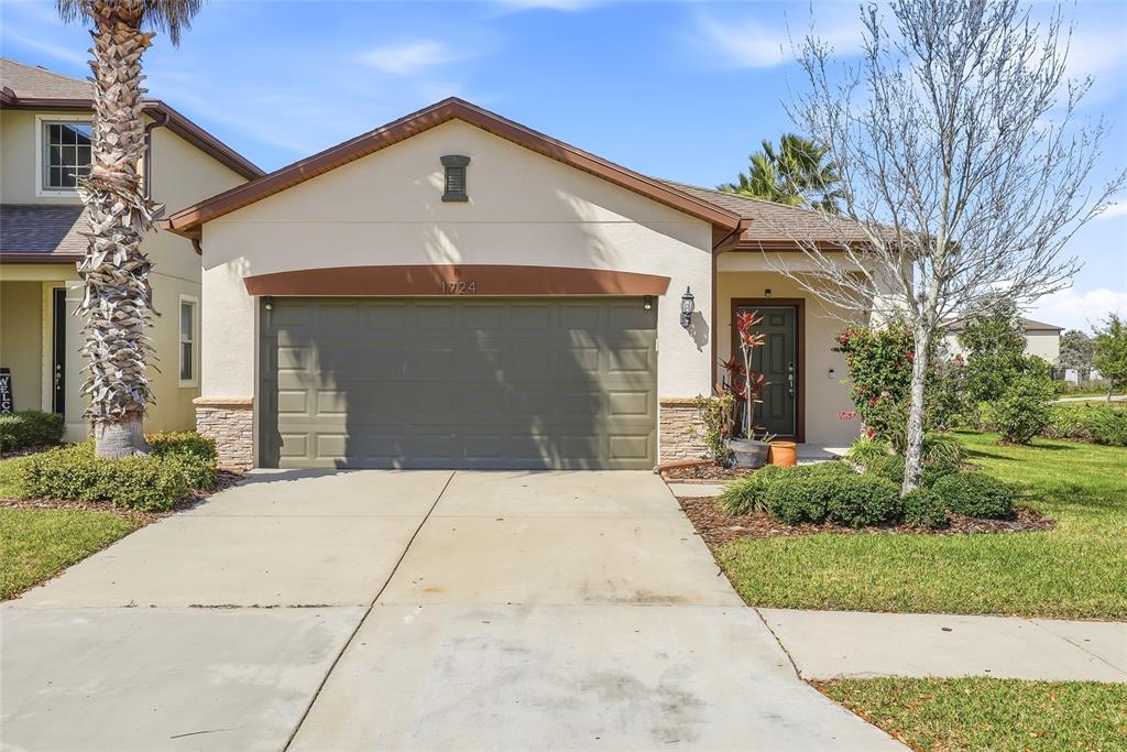 A single-story house with a beige stucco exterior, a two-car garage, and a front walkway — 1724 PASSAGE KEY LANE, RUSKIN, FL