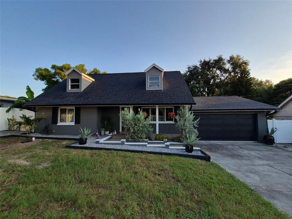 A gray two-story house with a dark roof, dormer windows, and a front-facing garage — 1504 BIG BASS DRIVE, TARPON SPRINGS, FL