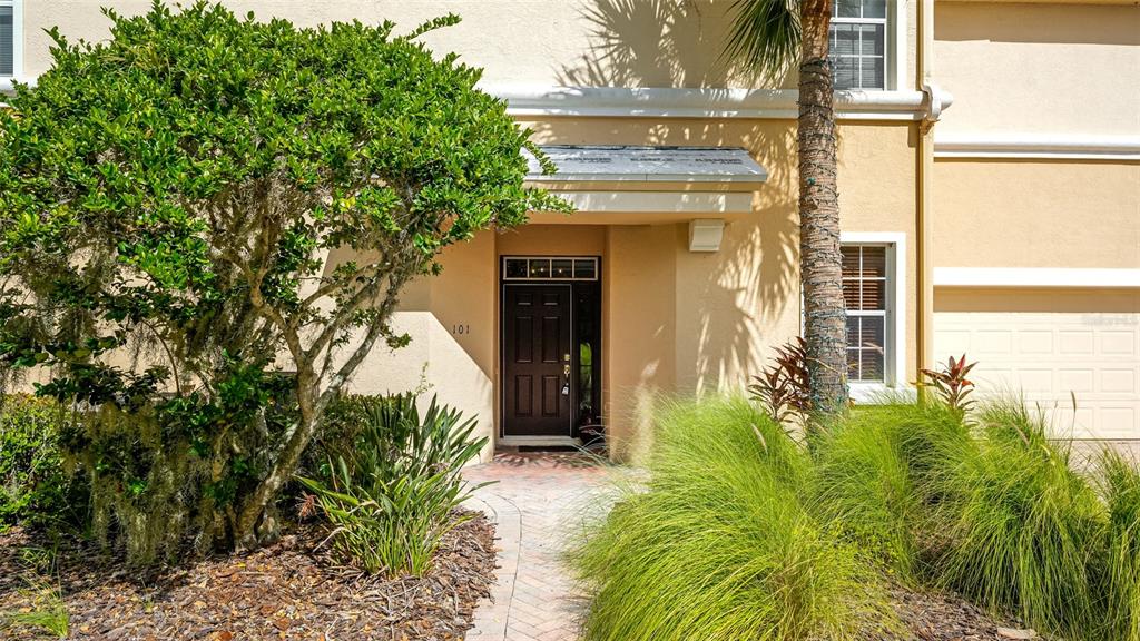 The exterior of a tan building features a dark front door labeled 101 and landscaping — 9454 DISCOVERY TERRACE UNIT 101A, BRADENTON, FL