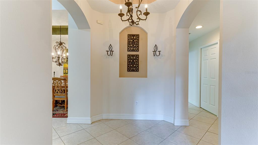 A tiled foyer features an arched wall niche with decorative panels and a chandelier — 9454 DISCOVERY TERRACE UNIT 101A, BRADENTON, FL