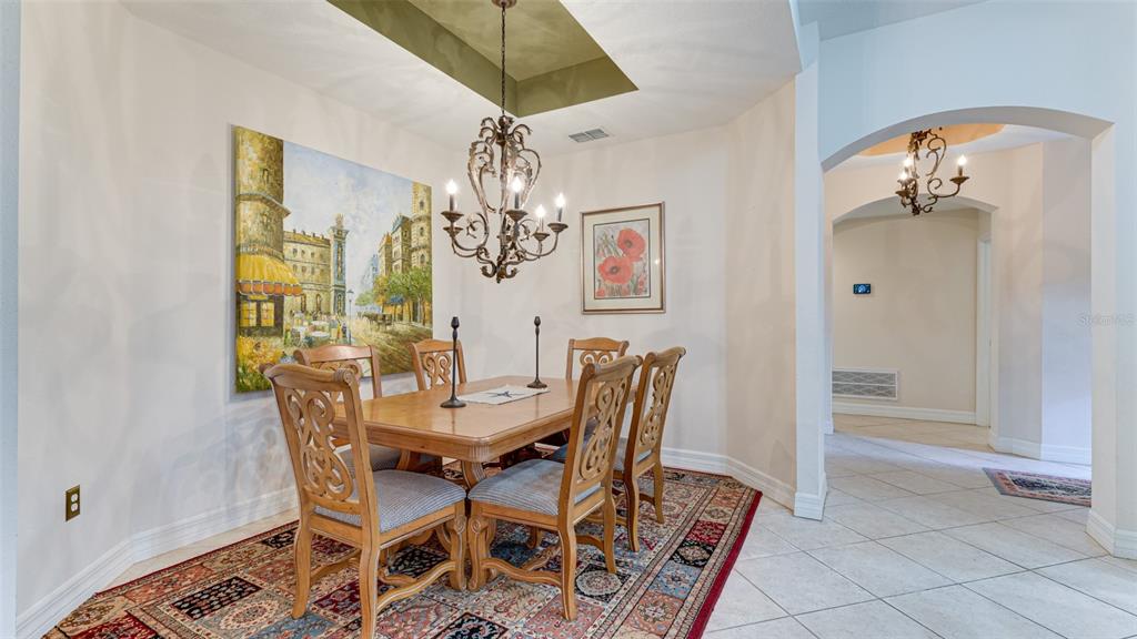 A dining room features a wooden table, six chairs, a chandelier, and a large wall painting — 9454 DISCOVERY TERRACE UNIT 101A, BRADENTON, FL