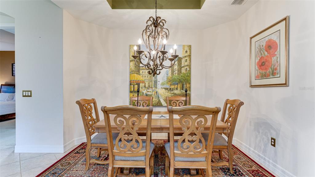 A dining room features a wooden table, six chairs, a chandelier, and a framed painting — 9454 DISCOVERY TERRACE UNIT 101A, BRADENTON, FL