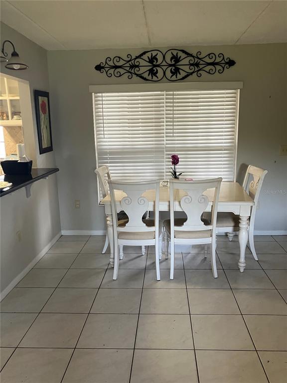 A dining area features a white table with four chairs, tile flooring, and a window — 316 N BAYSHORE BOULEVARD UNIT 105, CLEARWATER, FL