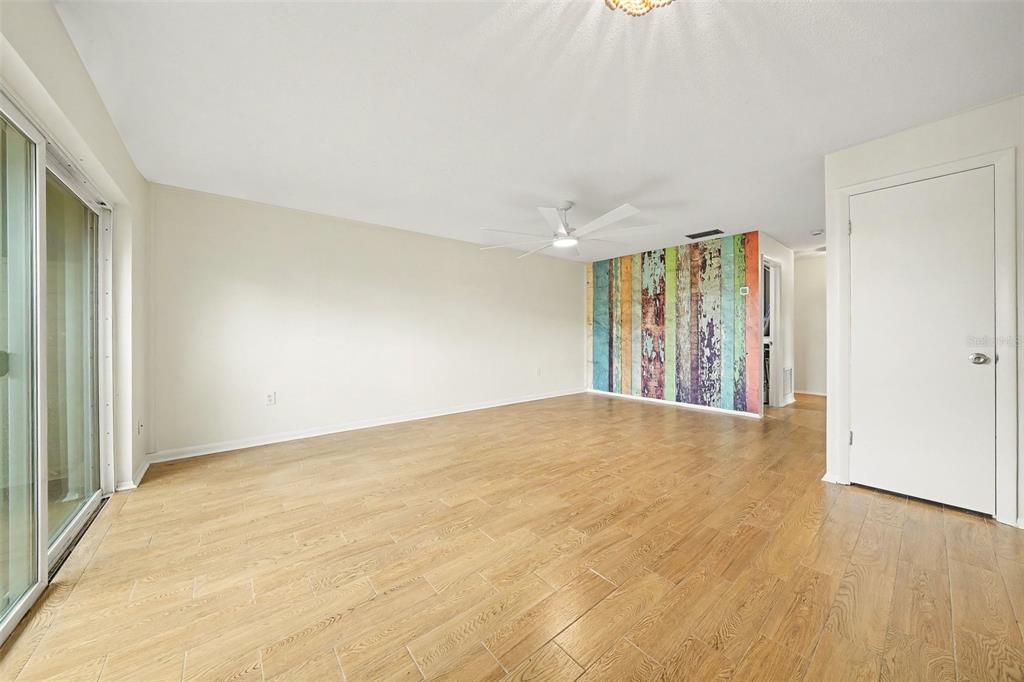 An empty room with wood-look tile flooring, a ceiling fan, and a colorful accent wall — 513 POLARIS LOOP UNIT 101, CASSELBERRY, FL