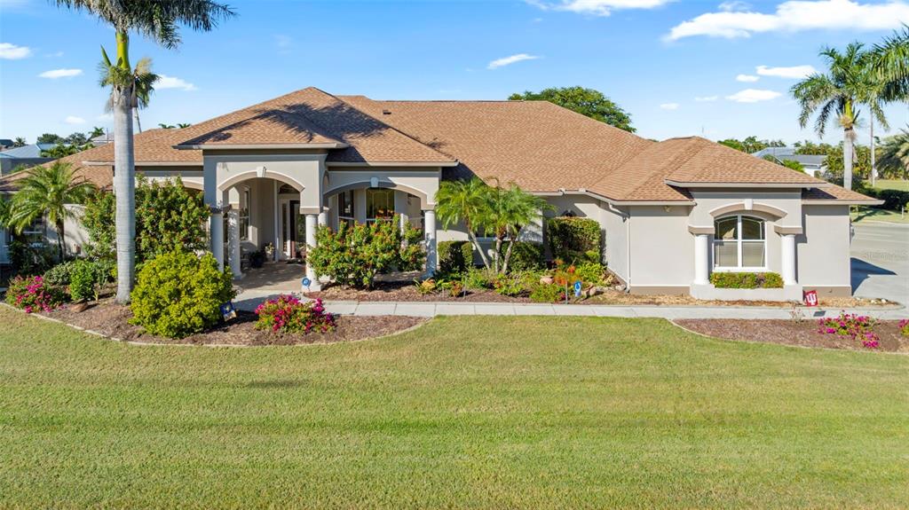 A single-story suburban house with a tan exterior, brown shingled roof, and landscaped front yard — 5323 EARLY TERRACE, PORT CHARLOTTE, FL