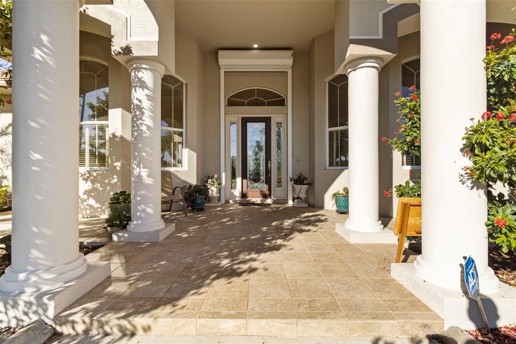 A covered entryway features tiled flooring, four white columns, and a glass-paneled front door — 5323 EARLY TERRACE, PORT CHARLOTTE, FL