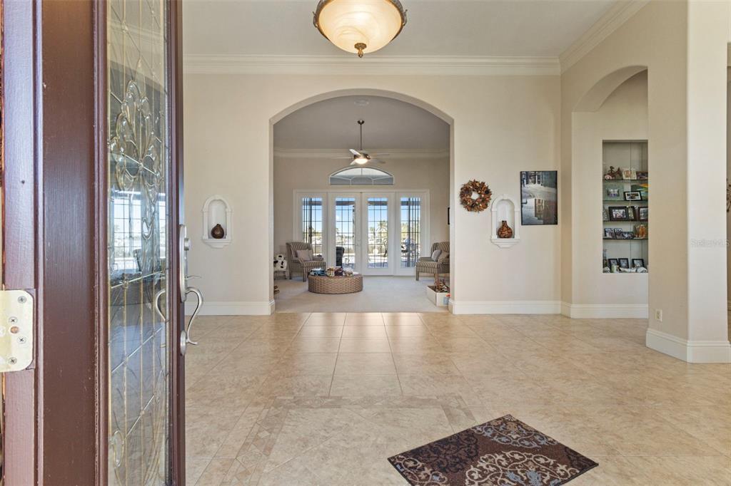 A view from an entryway into a living room with tile floors and arched openings — 5323 EARLY TERRACE, PORT CHARLOTTE, FL