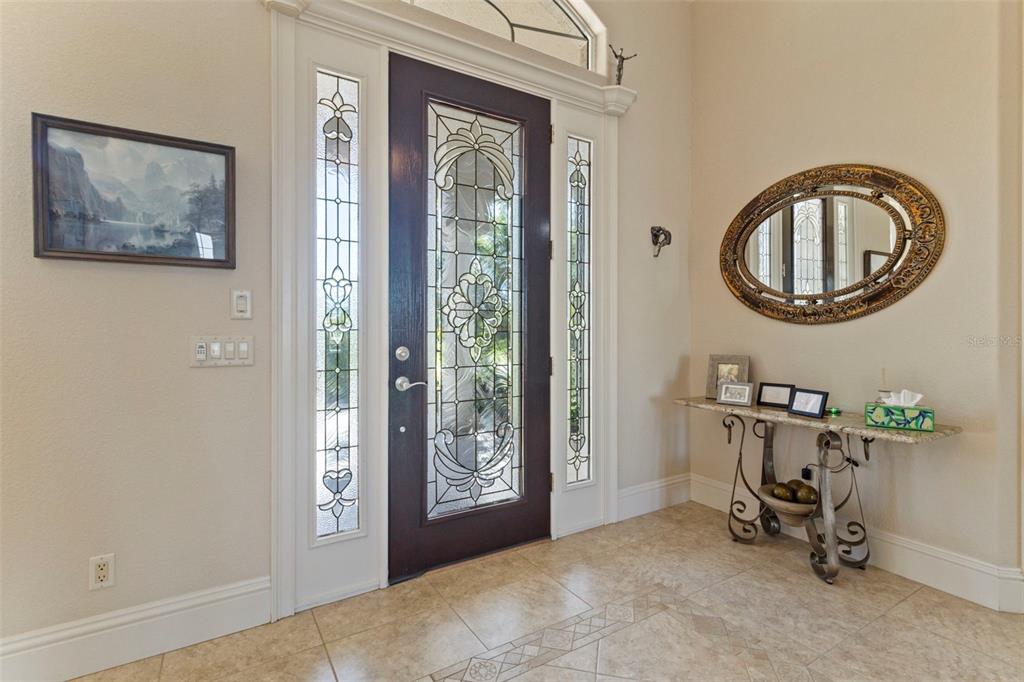An entryway features a dark wood front door with glass panels, tile flooring, and a mirror — 5323 EARLY TERRACE, PORT CHARLOTTE, FL