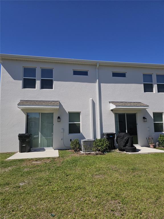 The rear exterior of a two-story townhouse features sliding glass doors and concrete patios — 3166 LAURENT LOOP, DAVENPORT, FL