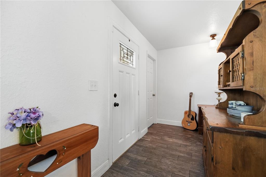 An entryway features wood-look tile flooring, a white front door, and a wooden hutch — 407 TENNESSEE AVENUE, ST CLOUD, FL
