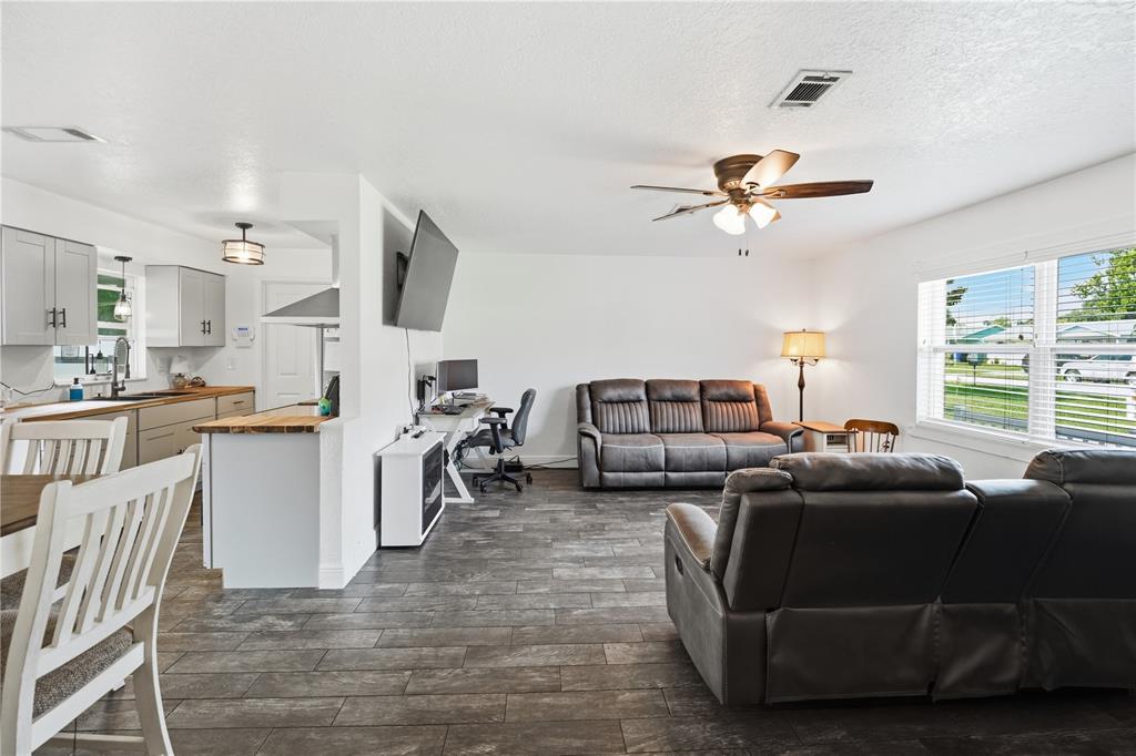 An open-concept living room and kitchen area with gray wood-look tile flooring and white walls — 407 TENNESSEE AVENUE, ST CLOUD, FL