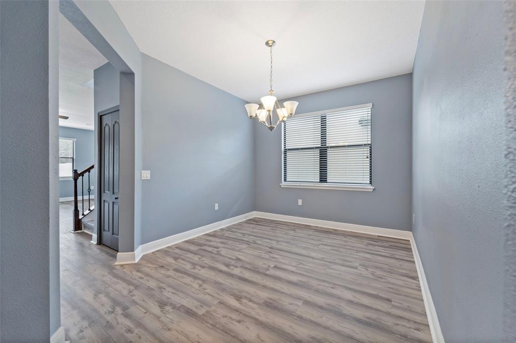 A dining room with light blue walls, wood-look flooring, and a central chandelier — 11006 TAHITI ISLE LANE, TAMPA, FL